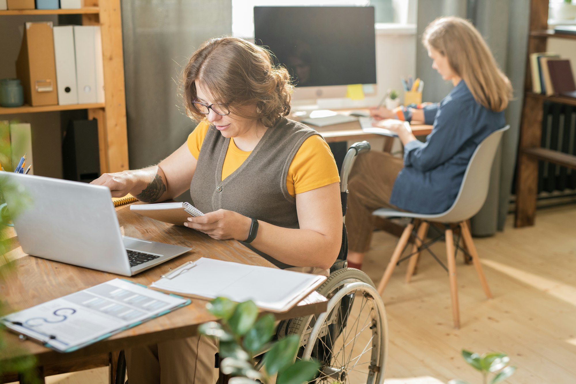 Young disable manager in casualwear sitting in wheelchair in front of laptop